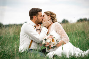 Brautpaar küsst sich auf der Wiese